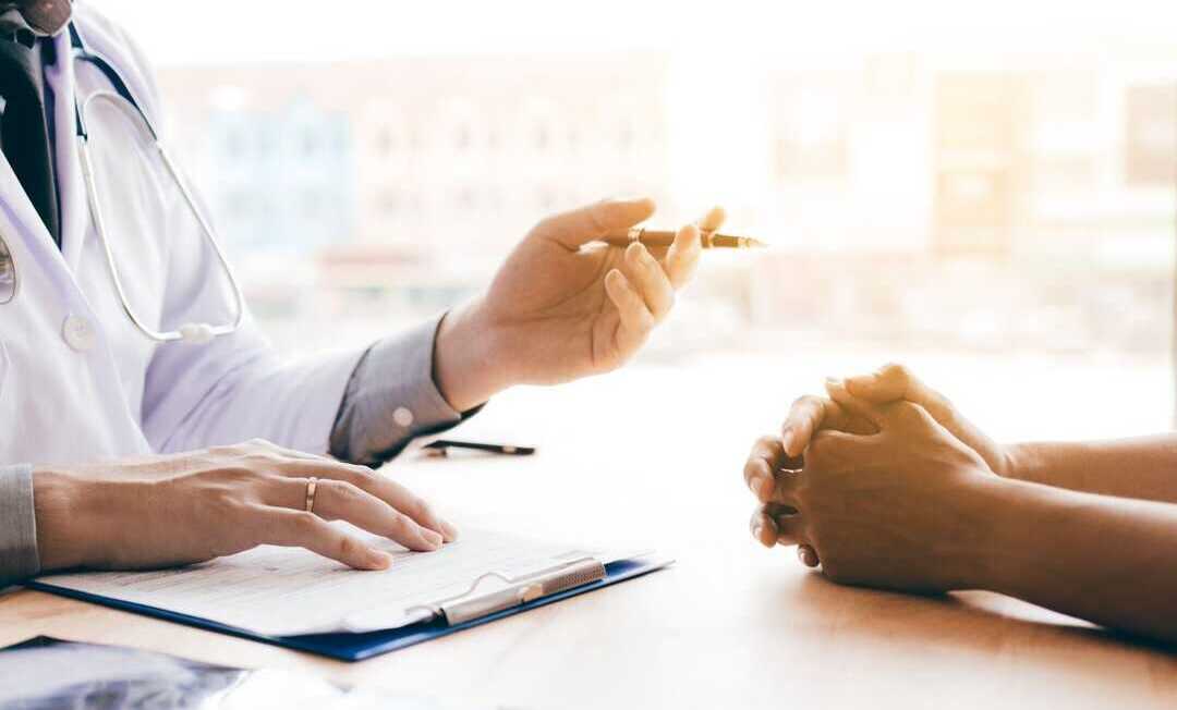 Doctor hand holding pen and talking to the patient about medication and treatment.