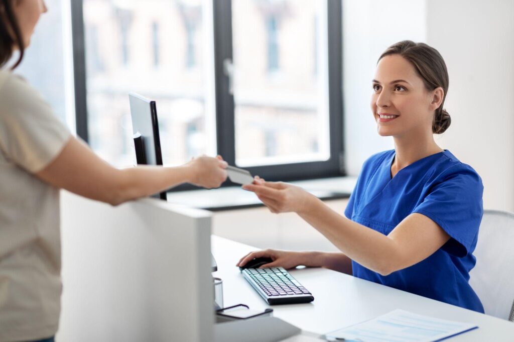 happy smiling female doctor or nurse and patient with credit card card at hospital